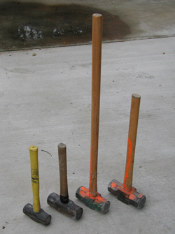 Multiple sledge hammers shown on a concrete pad to show the different handle lengths that are available