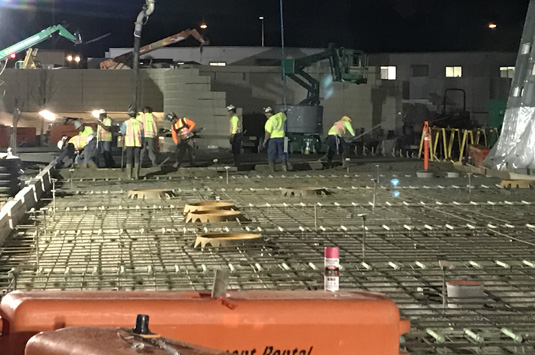 A night-time cement mason crew works on a job-site to build our world